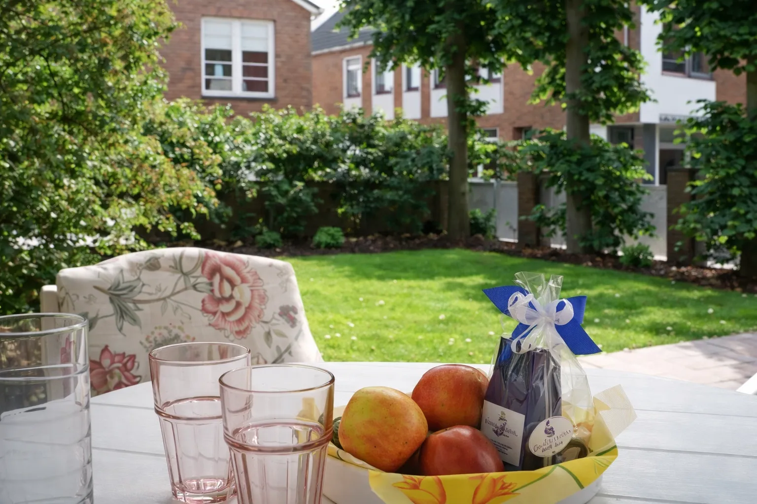 Gemütlicher Gartenplatz mit Obstkorb, Gläsern und Blick ins Grüne