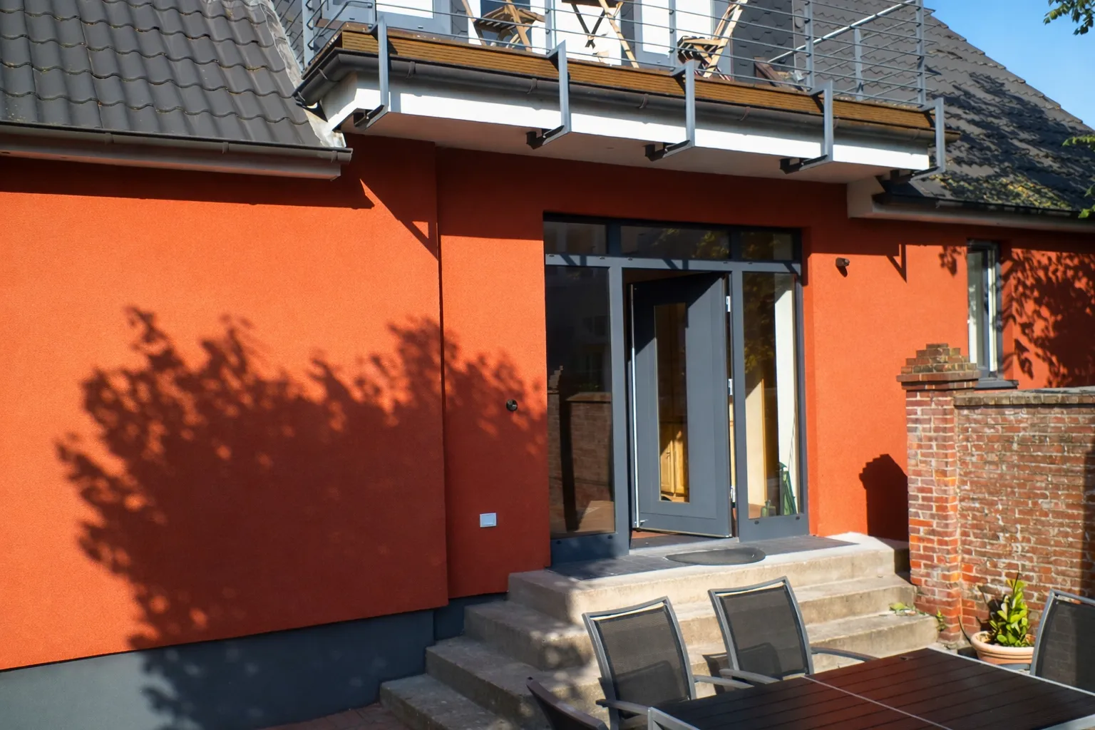 Terrasseneingang des Ferienhauses Roter Seestern mit Gartenmöbeln und Balkon darüber